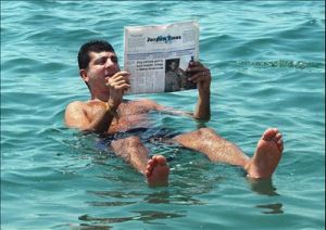 A man reading a newspaper while floating in the Dead Sea